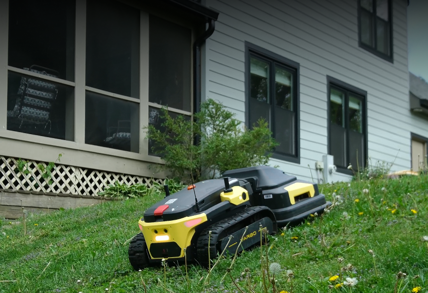 Yarbo robot lawn mower navigating a steep slope next to a house